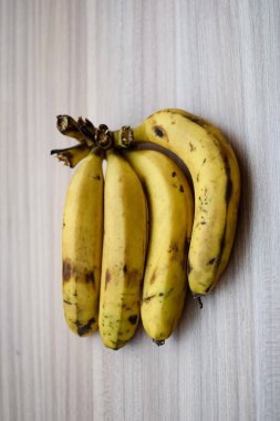 Sade ahşap masada taze meyve muzu, tüm temel yiyecekler için temel meyveler, sade arka planda soyulmamış taze muz manzarası.