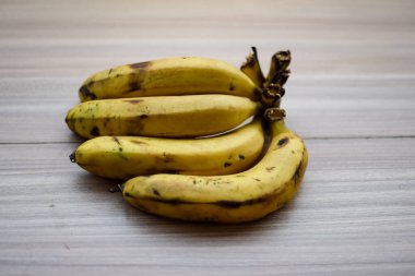 Sade ahşap masada taze meyve muzu, tüm temel yiyecekler için temel meyveler, sade arka planda soyulmamış taze muz manzarası.