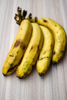 Sade ahşap masada taze meyve muzu, tüm temel yiyecekler için temel meyveler, sade arka planda soyulmamış taze muz manzarası.