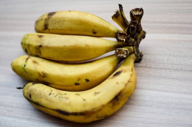 Sade ahşap masada taze meyve muzu, tüm temel yiyecekler için temel meyveler, sade arka planda soyulmamış taze muz manzarası.