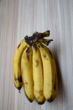 Sade ahşap masada taze meyve muzu, tüm temel yiyecekler için temel meyveler, sade arka planda soyulmamış taze muz manzarası.