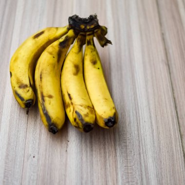 Sade ahşap masada taze meyve muzu, tüm temel yiyecekler için temel meyveler, sade arka planda soyulmamış taze muz manzarası.