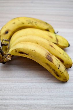 Sade ahşap masada taze meyve muzu, tüm temel yiyecekler için temel meyveler, sade arka planda soyulmamış taze muz manzarası.