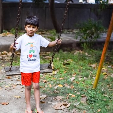 Sosyete parkında salıncakta sallanan zeki Asyalı çocuk, yazın dışarıda oynayan mutlu çocuk, bahçede salıncakta sallanan bebek..