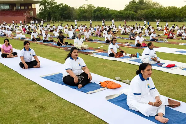 Yeni Delhi, Hindistan, 21 Haziran 2023 - Uluslararası Yoga Günü 'nde Delhi' deki Yamuna Spor Kompleksi 'nde grup Yoga egzersiz oturumu, kriket stadyumunda yoga derslerine katılan büyük bir grup yetişkin