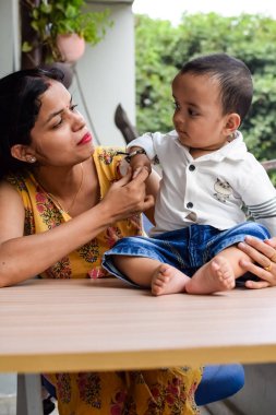 Sevgi dolu anne bebeğini balkonda taşıyor. Mutlu bir annenin parlak portresi. Çocuğu elinde tutuyor. Anne ve 1 yaşındaki küçük oğlu..