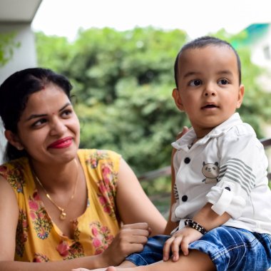 Sevgi dolu anne bebeğini balkonda taşıyor. Mutlu bir annenin parlak portresi. Çocuğu elinde tutuyor. Anne ve 1 yaşındaki küçük oğlu..