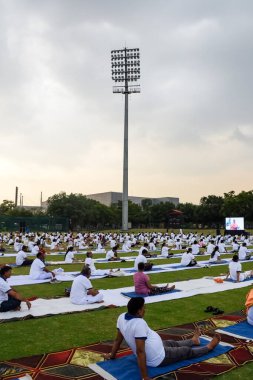 Yeni Delhi, Hindistan, 21 Haziran 2023 - Uluslararası Yoga Günü 'nde Delhi' deki Yamuna Spor Kompleksi 'nde grup Yoga egzersiz oturumu, kriket stadyumunda yoga derslerine katılan büyük bir grup yetişkin