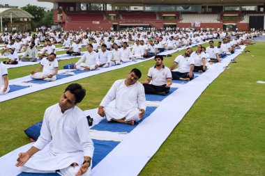 Yeni Delhi, Hindistan, 21 Haziran 2023 - Uluslararası Yoga Günü 'nde Delhi' deki Yamuna Spor Kompleksi 'nde grup Yoga egzersiz oturumu, kriket stadyumunda yoga derslerine katılan büyük bir grup yetişkin