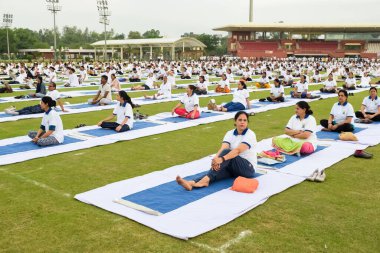Yeni Delhi, Hindistan, 21 Haziran 2023 - Uluslararası Yoga Günü 'nde Delhi' deki Yamuna Spor Kompleksi 'nde grup Yoga egzersiz oturumu, kriket stadyumunda yoga derslerine katılan büyük bir grup yetişkin