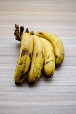 Sade ahşap masada taze muz, tüm temel gıdalar için taze temel meyveler, sade arka planda soyulmamış meyvelerin manzarası..