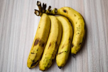 Sade ahşap masada taze muz, tüm temel gıdalar için taze temel meyveler, sade arka planda soyulmamış meyvelerin manzarası..