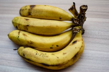 Sade ahşap masada taze muz, tüm temel gıdalar için taze temel meyveler, sade arka planda soyulmamış meyvelerin manzarası..