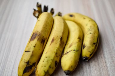 Sade ahşap masada taze muz, tüm temel gıdalar için taze temel meyveler, sade arka planda soyulmamış meyvelerin manzarası..