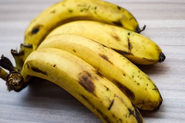 Sade ahşap masada taze muz, tüm temel gıdalar için taze temel meyveler, sade arka planda soyulmamış meyvelerin manzarası..