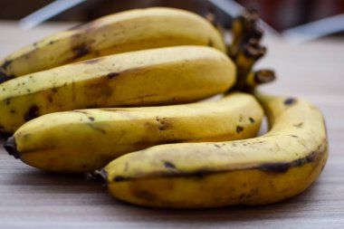 Sade ahşap masada taze muz, tüm temel gıdalar için taze temel meyveler, sade arka planda soyulmamış meyvelerin manzarası..