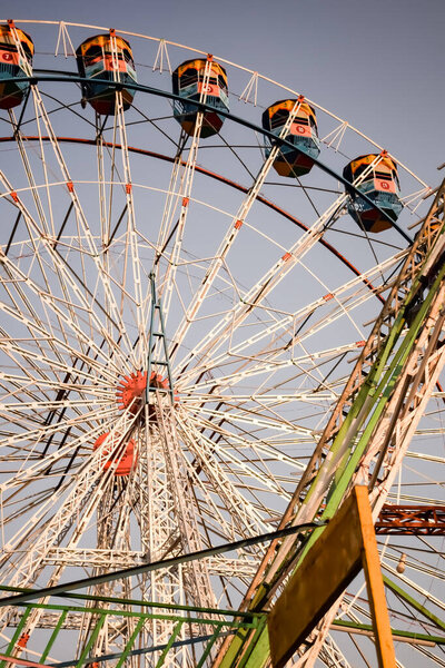 Closeup of multi-coloured Giant Wheel during Dussehra Mela in Delhi, India. Bottom view of Giant Wheel swing. Ferriswheel with colourful cabins during day time.