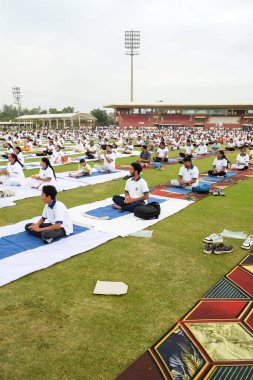 Yeni Delhi, Hindistan, 21 Haziran 2023 - Uluslararası Yoga Günü 'nde Delhi' deki Yamuna Spor Kompleksi 'nde grup Yoga egzersiz oturumu, kriket stadyumunda yoga derslerine katılan büyük bir grup yetişkin