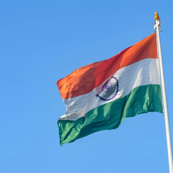 stock image India flag flying high at Connaught Place with pride in blue sky, India flag fluttering, Indian Flag on Independence Day and Republic Day of India, tilt up shot, Waving Indian flag, Har Ghar Tiranga