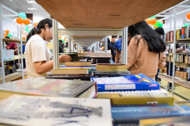 Delhi, Hindistan, Eylül 09 2023 - Çeşitli yaş grupları Delhi Uluslararası Kitap Fuarı 'ndaki bir kitaplığın içinde çeşitli kitaplar okuyor, Yıllık Kitap Fuarı' nda kitap seçimleri