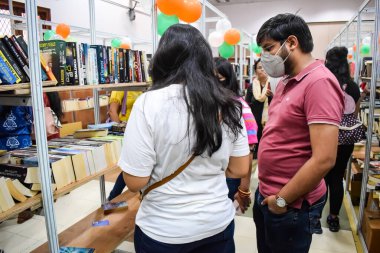 Delhi, Hindistan, Eylül 09 2023 - Çeşitli yaş grupları Delhi Uluslararası Kitap Fuarı 'ndaki bir kitaplığın içinde çeşitli kitaplar okuyor, Yıllık Kitap Fuarı' nda kitap seçimleri