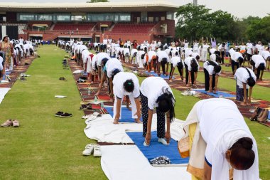 Yeni Delhi, Hindistan, 21 Haziran 2023 - Uluslararası Yoga Günü 'nde Delhi' deki Yamuna Spor Kompleksi 'nde grup Yoga egzersiz oturumu, kriket stadyumunda yoga derslerine katılan büyük bir grup yetişkin