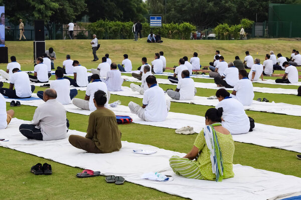 New Delhi, India, June 21, 2023 - Group Yoga exercise session for people at Yamuna Sports Complex in Delhi on International Yoga Day, Big group of adults attending yoga class in cricket stadium