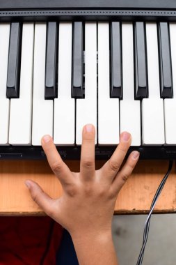 Sentezleyici ya da piyano çalan Asyalı çocuk. Küçük şirin çocuk piyano çalmayı öğreniyor. Çocuk elleri klavyenin içinde..