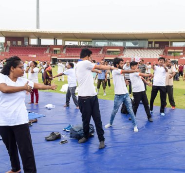 Yeni Delhi, Hindistan, 21 Haziran 2023 - Uluslararası Yoga Günü 'nde Delhi' deki Yamuna Spor Kompleksi 'nde grup Yoga egzersiz oturumu, kriket stadyumunda yoga derslerine katılan büyük bir grup yetişkin