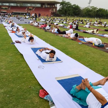 Yeni Delhi, Hindistan, 21 Haziran 2023 - Uluslararası Yoga Günü 'nde Delhi' deki Yamuna Spor Kompleksi 'nde grup Yoga egzersiz oturumu, kriket stadyumunda yoga derslerine katılan büyük bir grup yetişkin