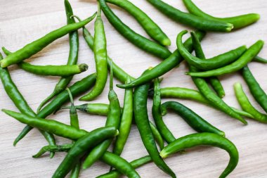Sade ahşap masada taze yeşil biber, tüm temel gıdalar için yeşil sebzeler, sade arka planda soyulmamış sebzelerin manzarası