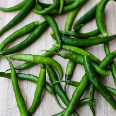 Sade ahşap masada taze yeşil biber, tüm temel gıdalar için yeşil sebzeler, sade arka planda soyulmamış sebzelerin manzarası