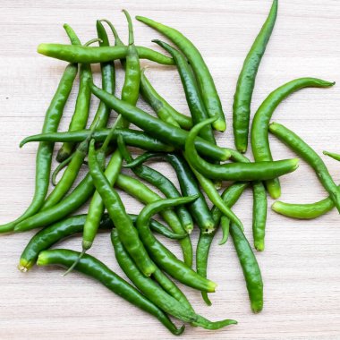 Sade ahşap masada taze yeşil biber, tüm temel gıdalar için yeşil sebzeler, sade arka planda soyulmamış sebzelerin manzarası