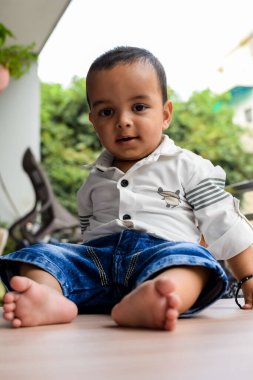 Erkek bebek balkonda. Masada oturan mutlu çocuğun parlak portresi. Evin balkonunda gündüz vakti 1 yaşında küçük bir çocuk..