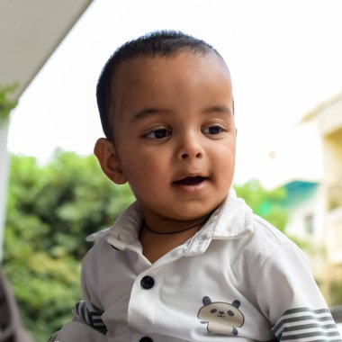 Erkek bebek balkonda. Masada oturan mutlu çocuğun parlak portresi. Evin balkonunda gündüz vakti 1 yaşında küçük bir çocuk..