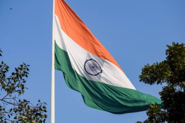India flag flying high at Connaught Place with pride in blue sky, India flag fluttering, Indian Flag on Independence Day and Republic Day of India, tilt up shot, Waving Indian flag, Har Ghar Tiranga