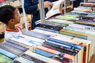 Delhi, Hindistan, Eylül 09 2023 - Çeşitli yaş grupları Delhi Uluslararası Kitap Fuarı 'ndaki bir kitaplığın içinde çeşitli kitaplar okuyor, Yıllık Kitap Fuarı' nda kitap seçimleri