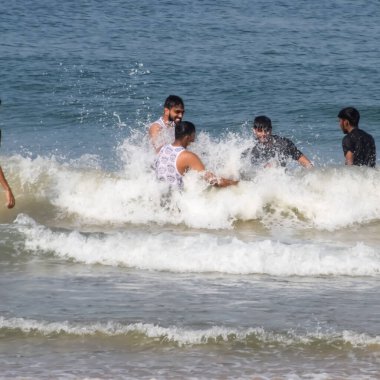 Goa, Hindistan, 10 Aralık 2023 - Sabahın erken saatlerinde Calangute plajı Goa 'da, Hindistan' da, Ocean plajı manzarasında, Arap denizinde eğlenen tanımlanamayan turistler