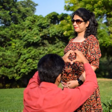 Hintli çift doğum çekimi için poz veriyor. Delhi 'deki Lodhi Road' da yeni doğan bebeğe kucak açıyorlar. Anne ve babalar çocuklarını karşıladıkları için annelik fotoğrafı çekiyorlar.