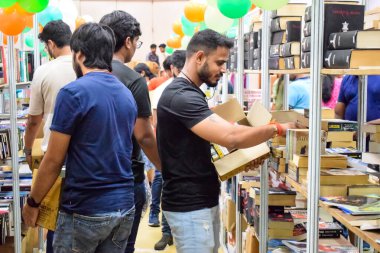 Delhi, Hindistan, Eylül 09 2023 - Çeşitli yaş grupları Delhi Uluslararası Kitap Fuarı 'ndaki bir kitaplığın içinde çeşitli kitaplar okuyor, Yıllık Kitap Fuarı' nda kitap seçimleri