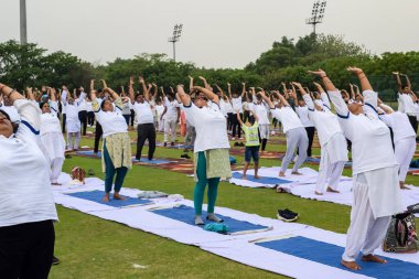 Yeni Delhi, Hindistan, 21 Haziran 2023 - Uluslararası Yoga Günü 'nde Delhi' deki Yamuna Spor Kompleksi 'nde grup Yoga egzersiz oturumu, kriket stadyumunda yoga derslerine katılan büyük bir grup yetişkin