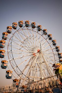 Delhi, Hindistan 'da Dussehra Mela sırasında çok renkli Dev Tekerlek' in yakın çekimi. Dev tekerlek salıncağının alt görüntüsü. Gündüz vakti renkli kamaralı dönme dolap.