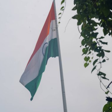 India flag flying high at Connaught Place with pride in blue sky, India flag fluttering, Indian Flag on Independence Day and Republic Day of India, tilt up shot, Waving Indian flag, Har Ghar Tiranga