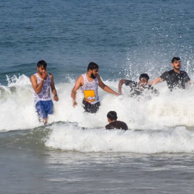 Goa, Hindistan, 10 Aralık 2023 - Sabahın erken saatlerinde Calangute plajı Goa 'da, Hindistan' da, Ocean plajı manzarasında, Arap denizinde eğlenen tanımlanamayan turistler