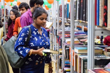 Delhi, Hindistan, Eylül 09 2023 - Çeşitli yaş grupları Delhi Uluslararası Kitap Fuarı 'ndaki bir kitaplığın içinde çeşitli kitaplar okuyor, Yıllık Kitap Fuarı' nda kitap seçimleri