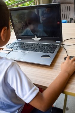 1. sınıftaki dizüstü bilgisayarını kullanan küçük bir çocuk, uzaktan eğitim için bilgisayarında okuyan bir çocuk, okul çocuğu yaşam tarzı konsepti.
