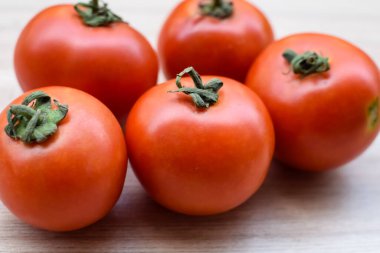 Sade ahşap masada kırmızı domates, tüm temel yiyecekler için gerekli sebzeler, sade arka planda soyulmamış sebzelerin manzarası.