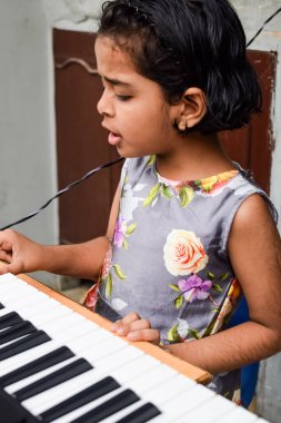Sentezleyici ya da piyano çalan Asyalı tatlı kız. Küçük şirin çocuk piyano çalmayı öğreniyor. Çocuk elleri klavyenin içinde..
