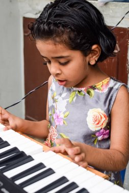 Sentezleyici ya da piyano çalan Asyalı tatlı kız. Küçük şirin çocuk piyano çalmayı öğreniyor. Çocuk elleri klavyenin içinde..