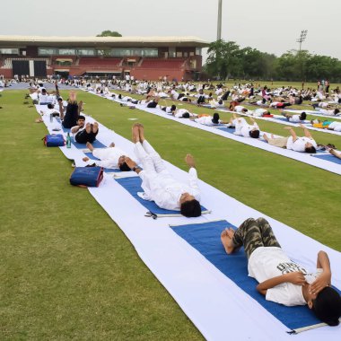 Yeni Delhi, Hindistan, 21 Haziran 2023 - Uluslararası Yoga Günü 'nde Delhi' deki Yamuna Spor Kompleksi 'nde grup Yoga egzersiz oturumu, kriket stadyumunda yoga derslerine katılan büyük bir grup yetişkin